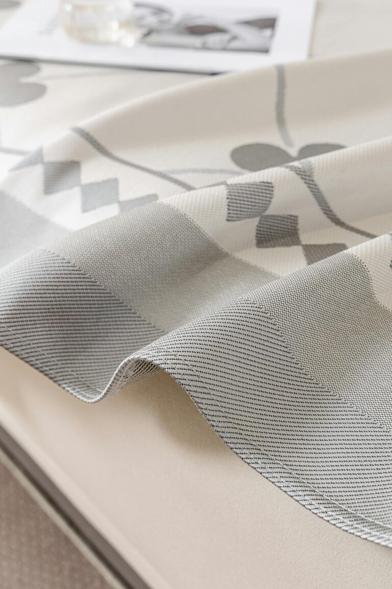 Elegant gray and white geometric pattern tablecloth draped over a table, perfect for modern home decor.