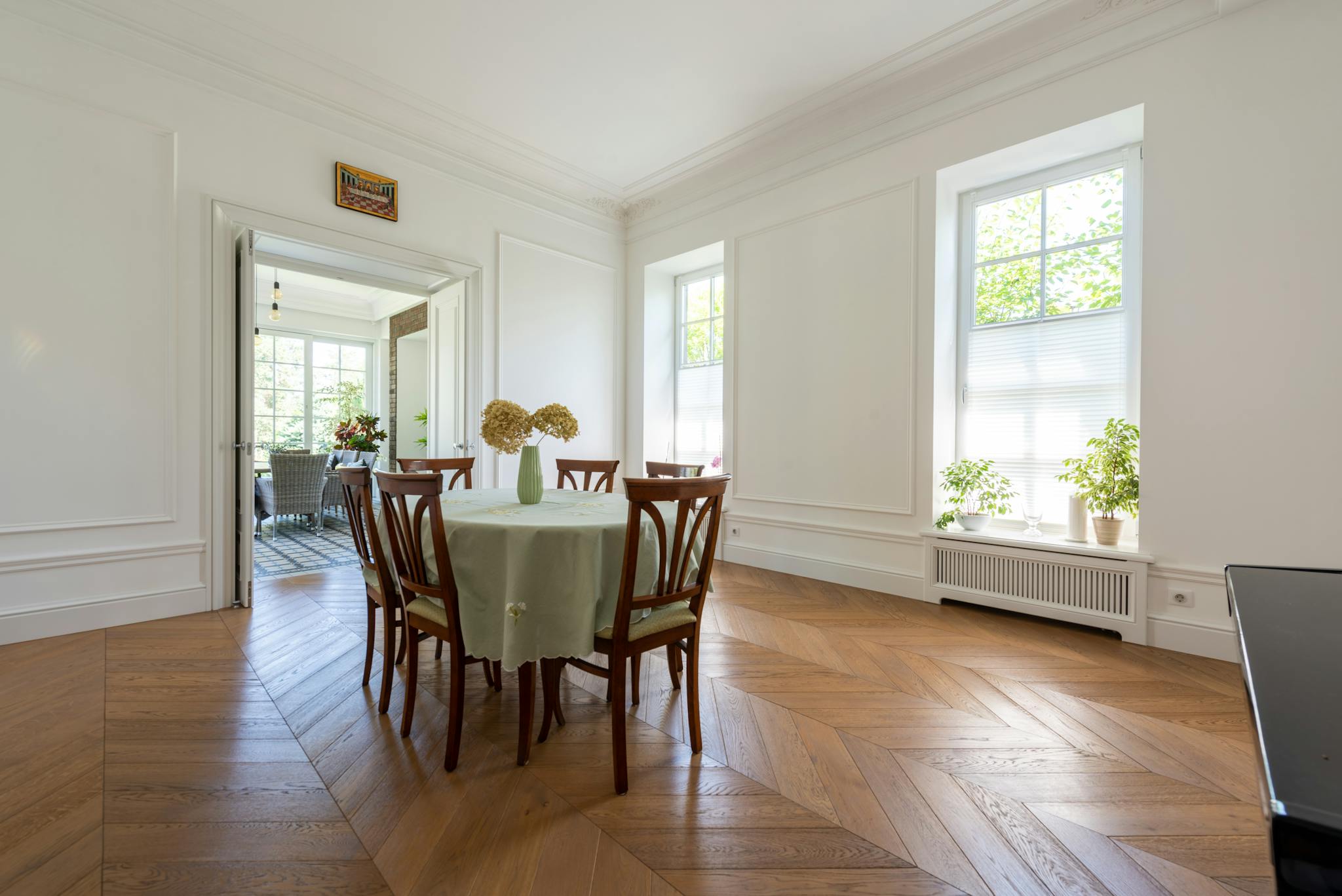Spacious dining room featuring a wooden table, white walls, and large windows.